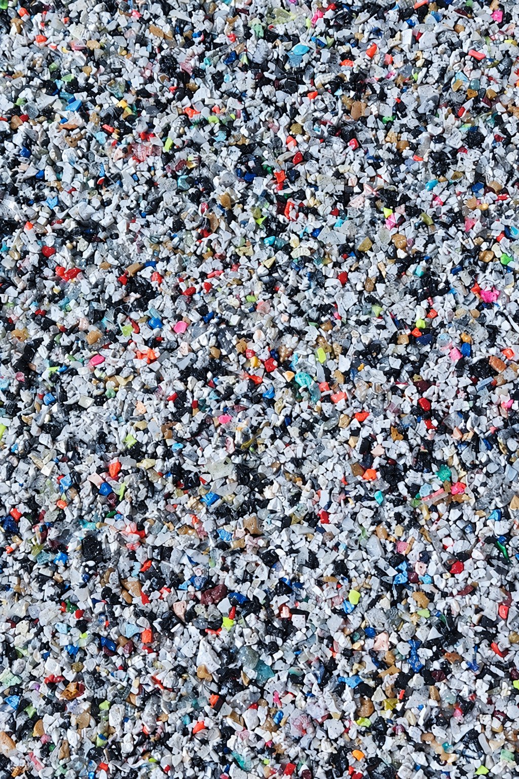 Recycled shoe rubber granules: grey, white and black chips with small coloured flecks.