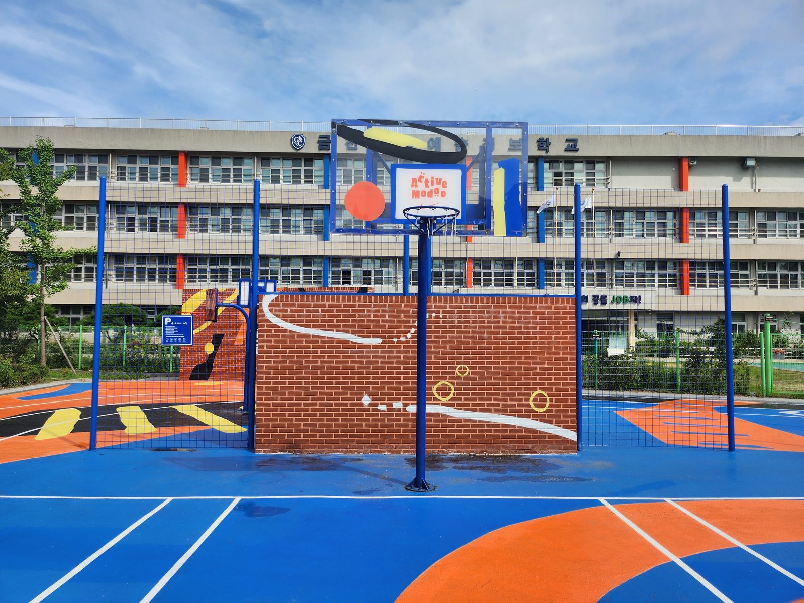 A brick-pattern rebound wall and a basketball hoop on the blue court surface.