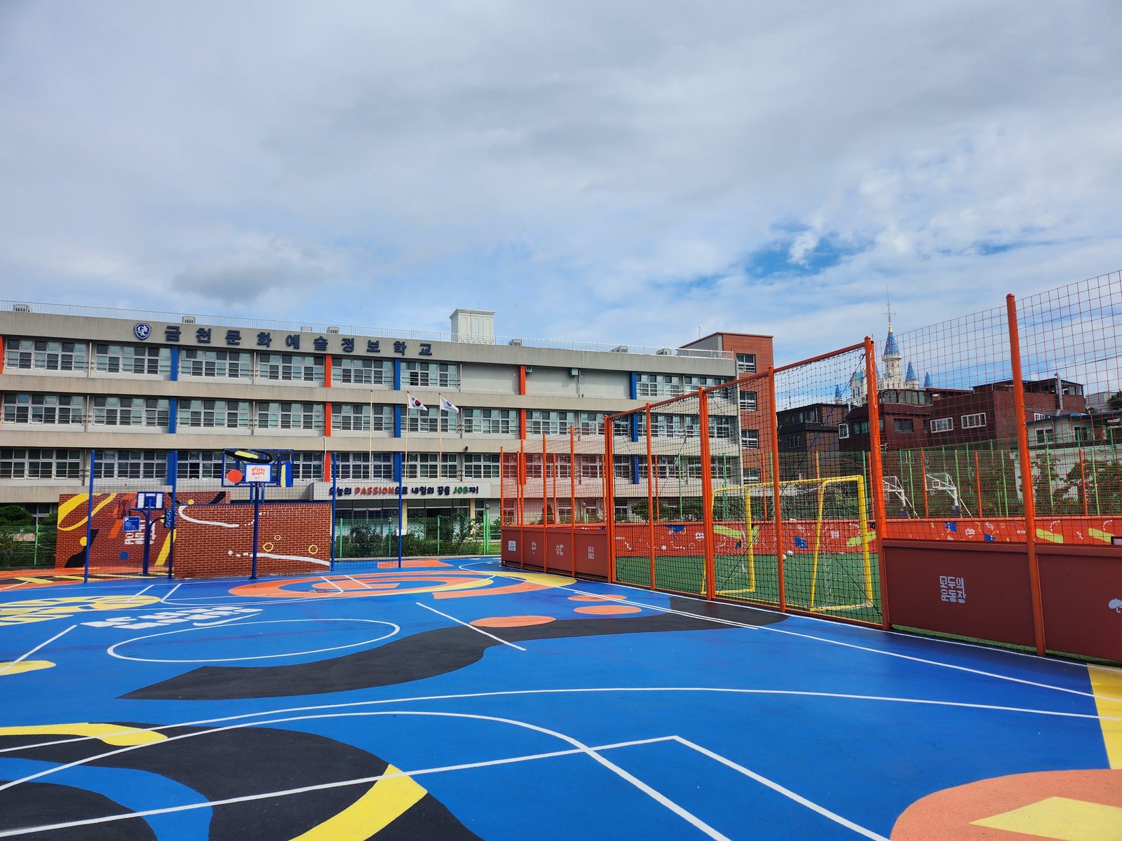 The Modoo Geumcheon court with orange fencing and a school building.